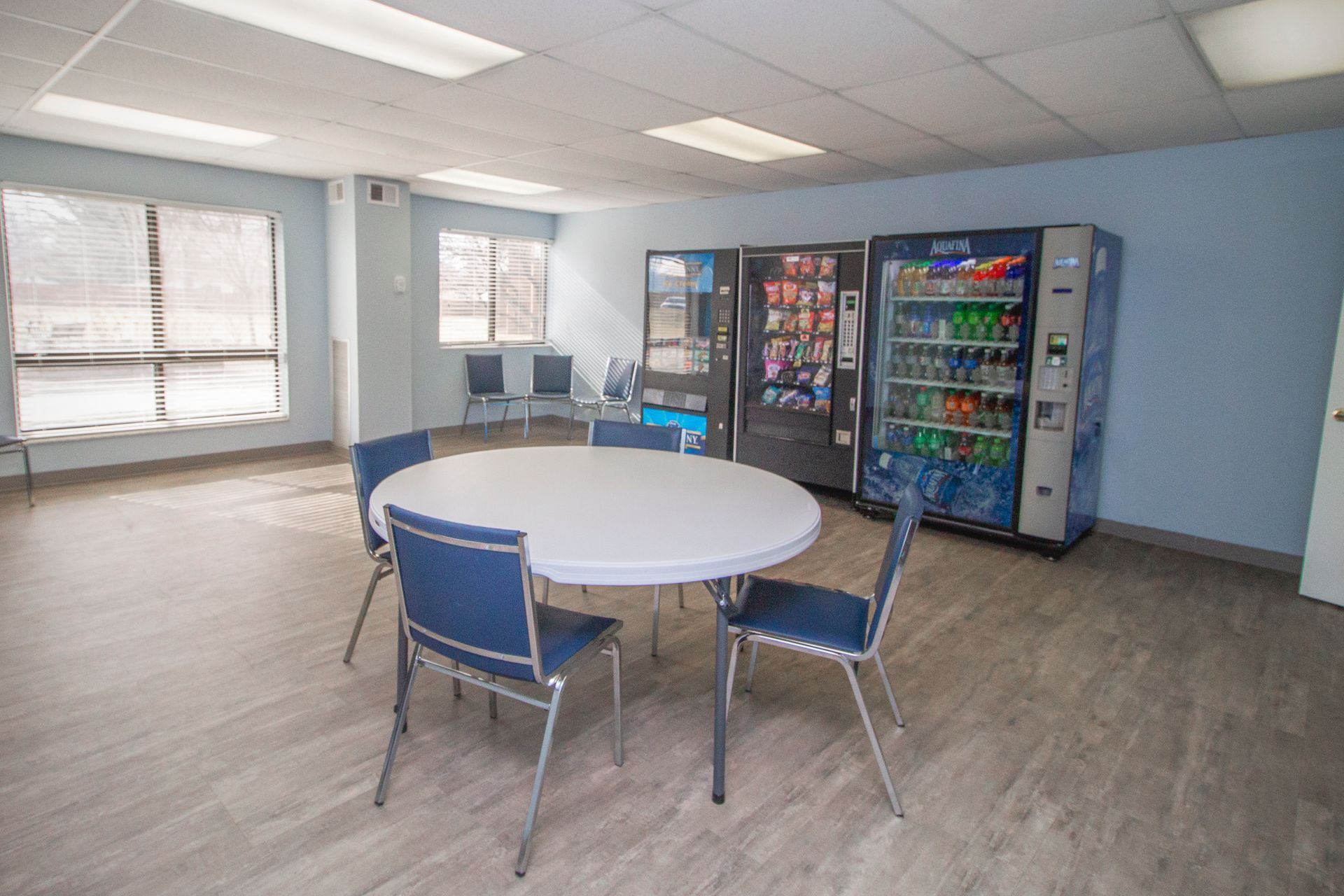 A room with a table and chairs and vending machines.