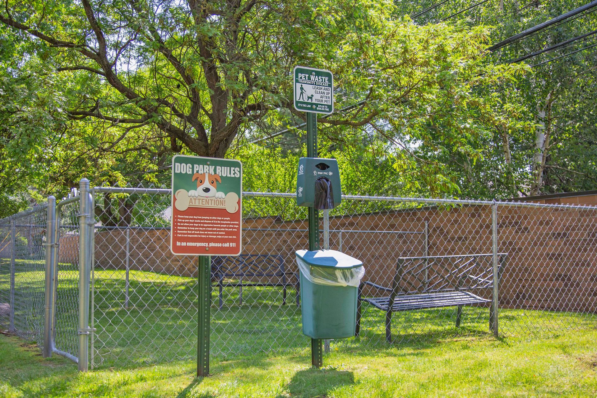 A dog park with a sign and a trash can
