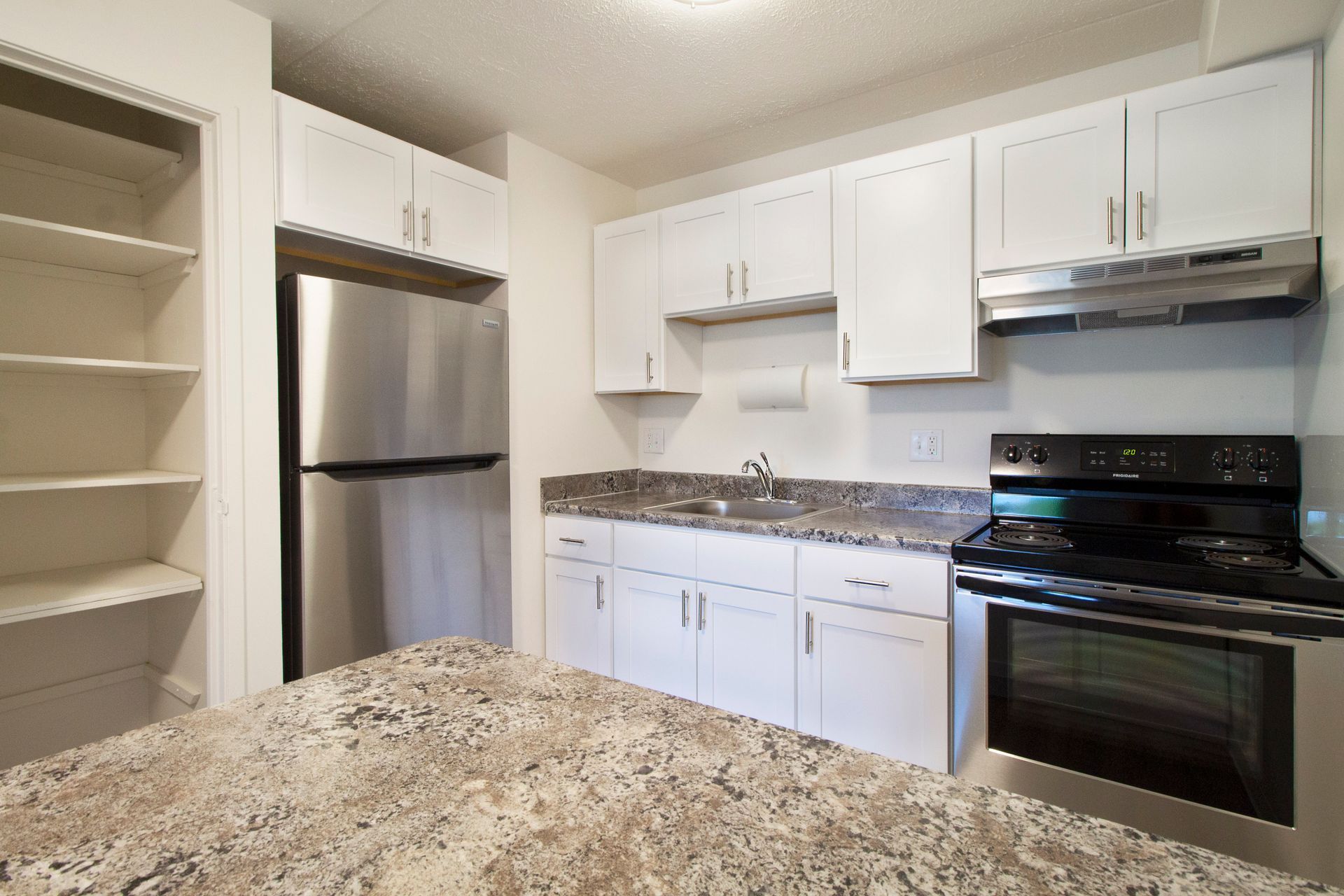 A kitchen with white cabinets stainless steel appliances and granite counter tops