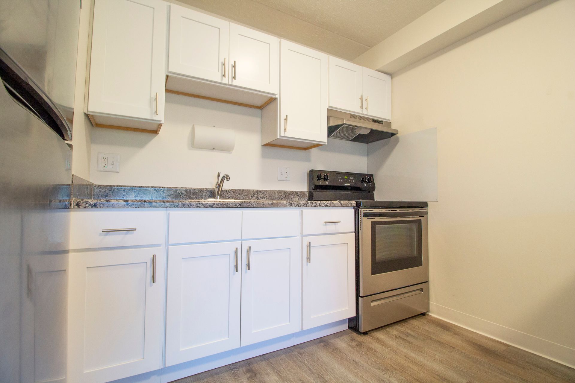 A kitchen with white cabinets , a stove , and a sink.