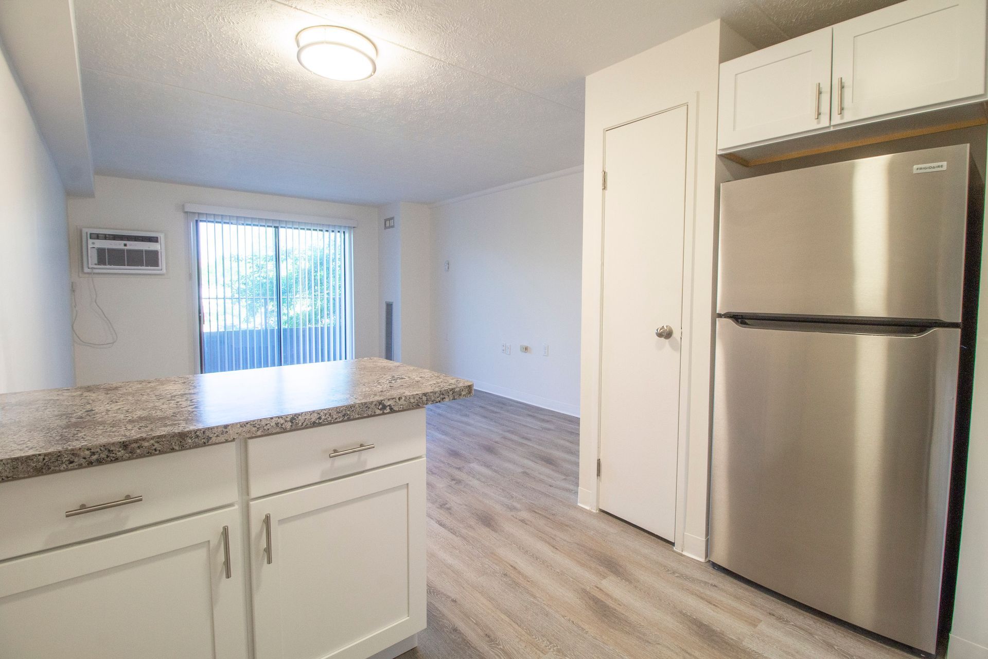A kitchen with a stainless steel refrigerator and white cabinets