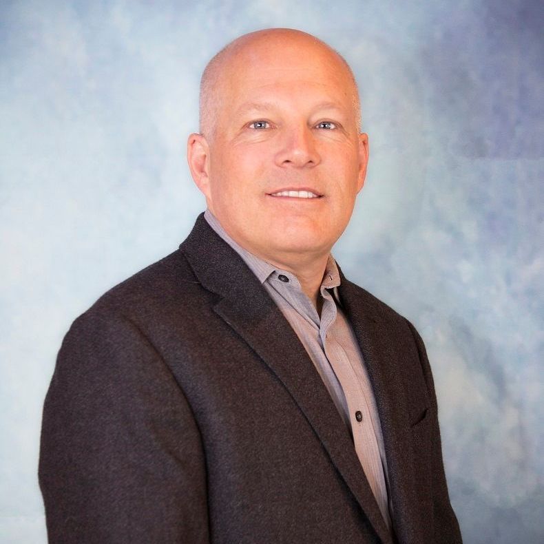 STEPHEN SWARTZ in a suit is smiling with his arms crossed.