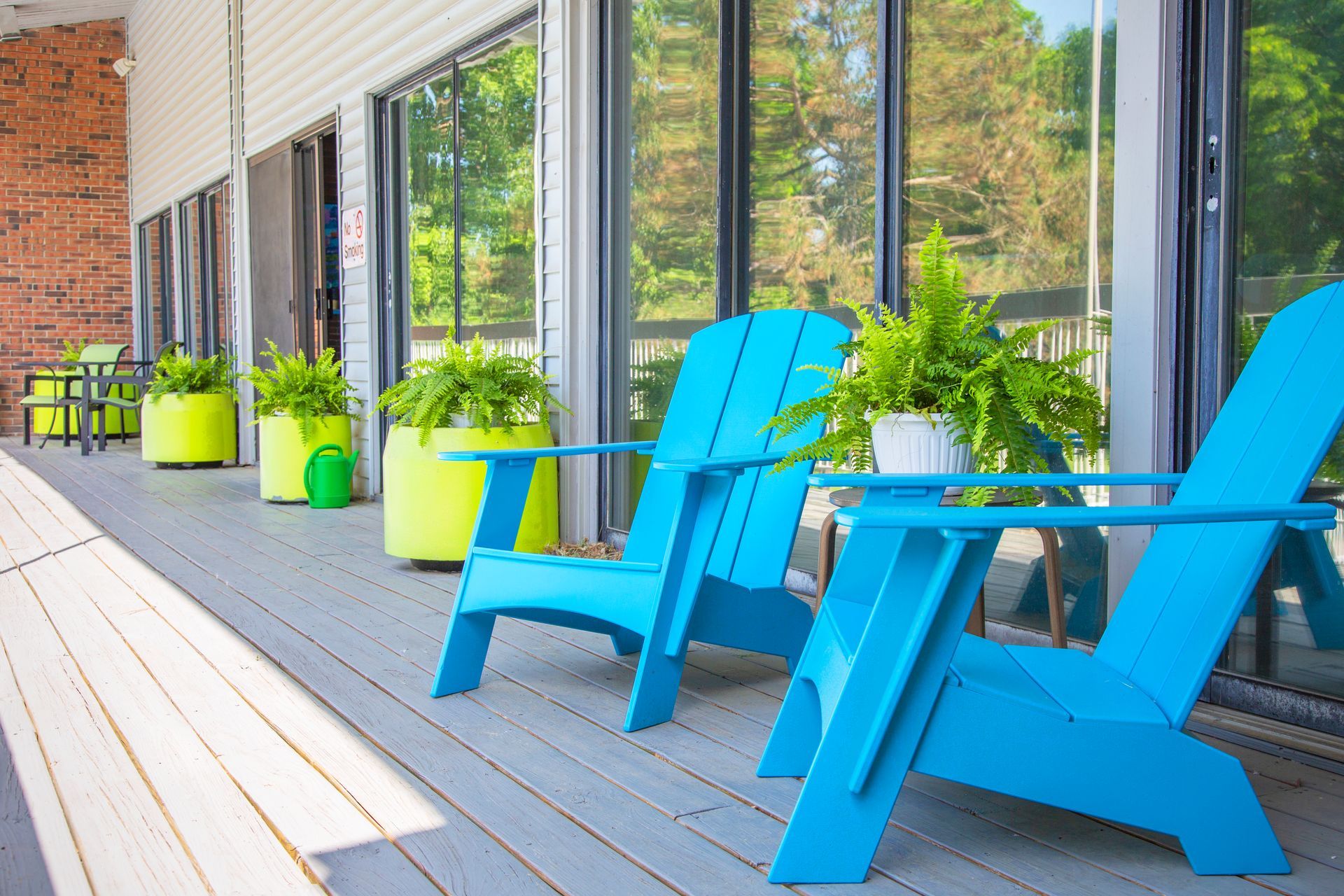 Two blue adirondack chairs are sitting on a deck in front of a building.