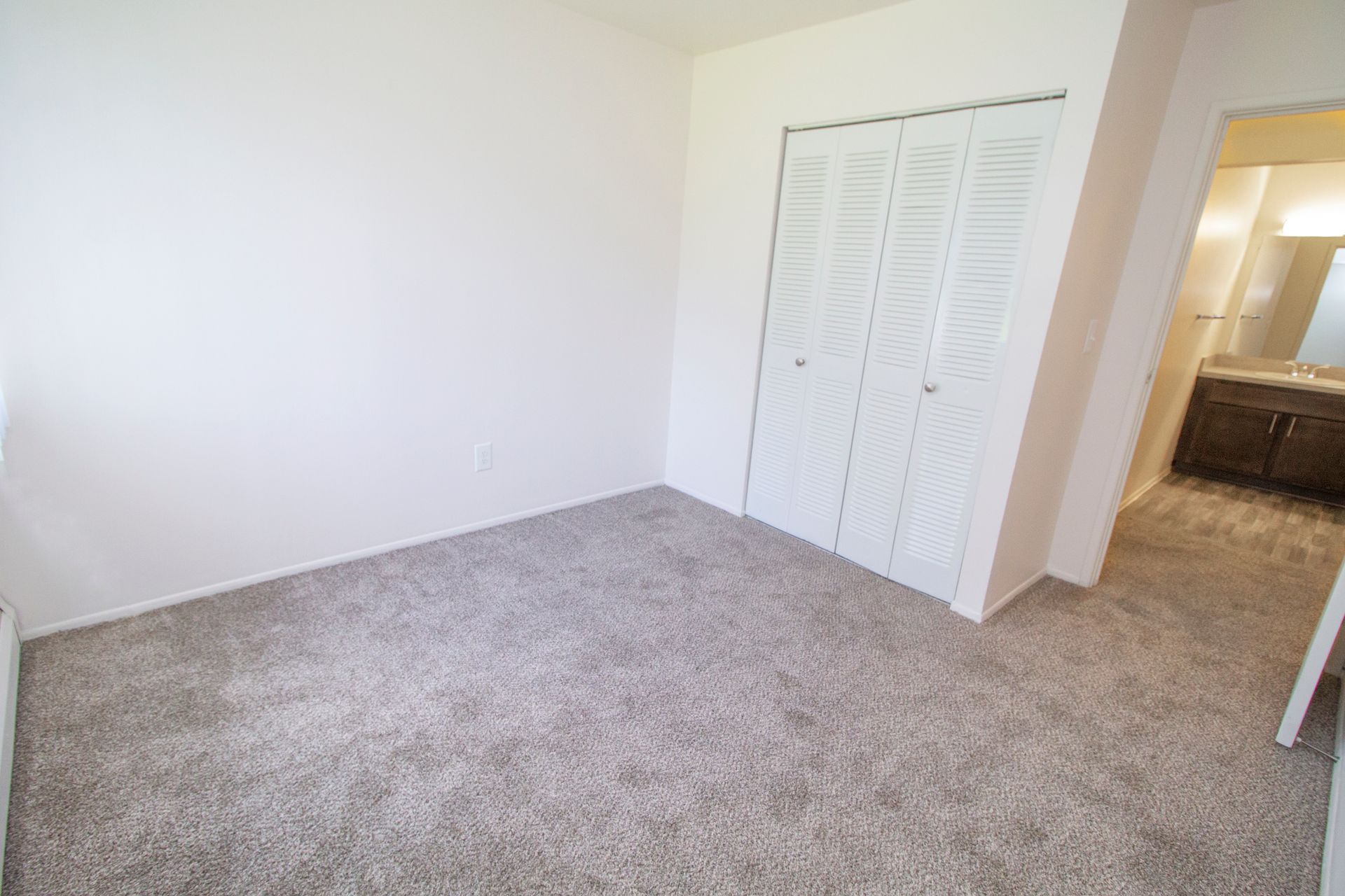 An empty bedroom with a closet and a bathroom.