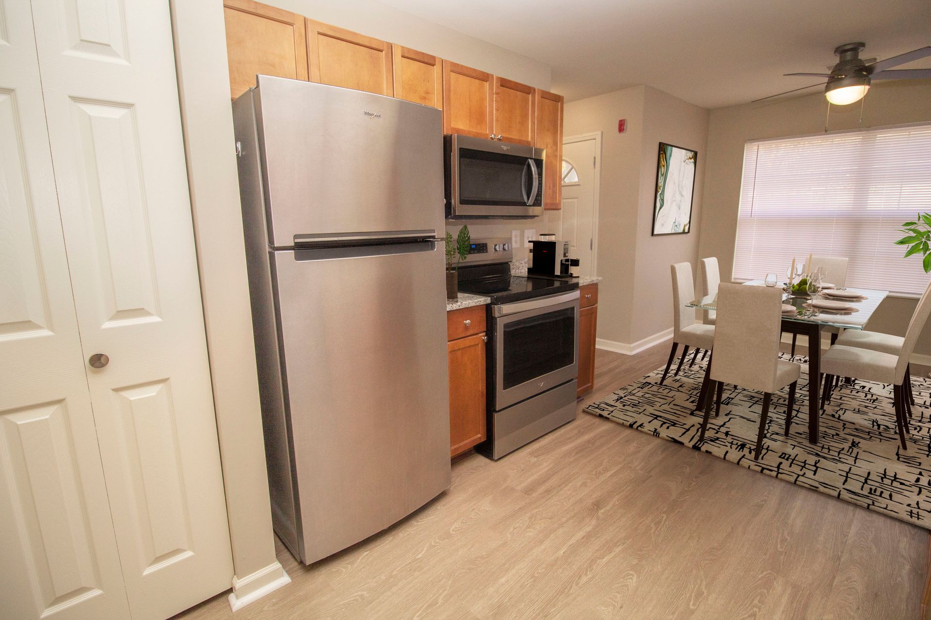 A kitchen with a refrigerator , stove , microwave and a ceiling fan.