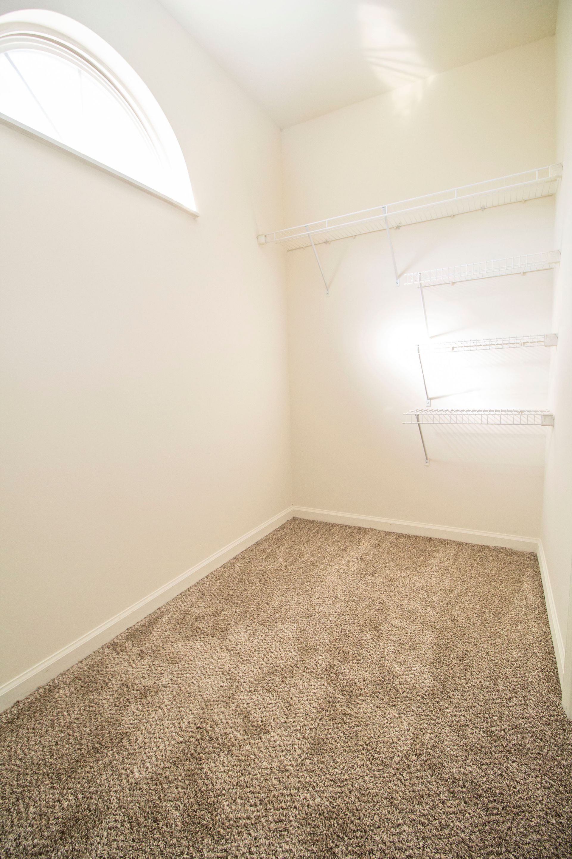 An empty room with a carpeted floor and a window.