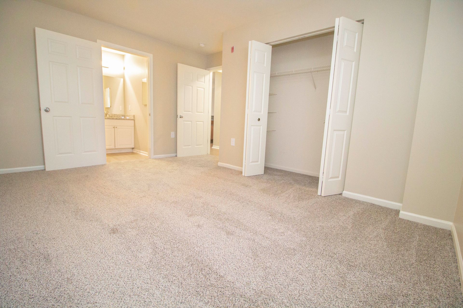 An empty bedroom with a closet and a bathroom.