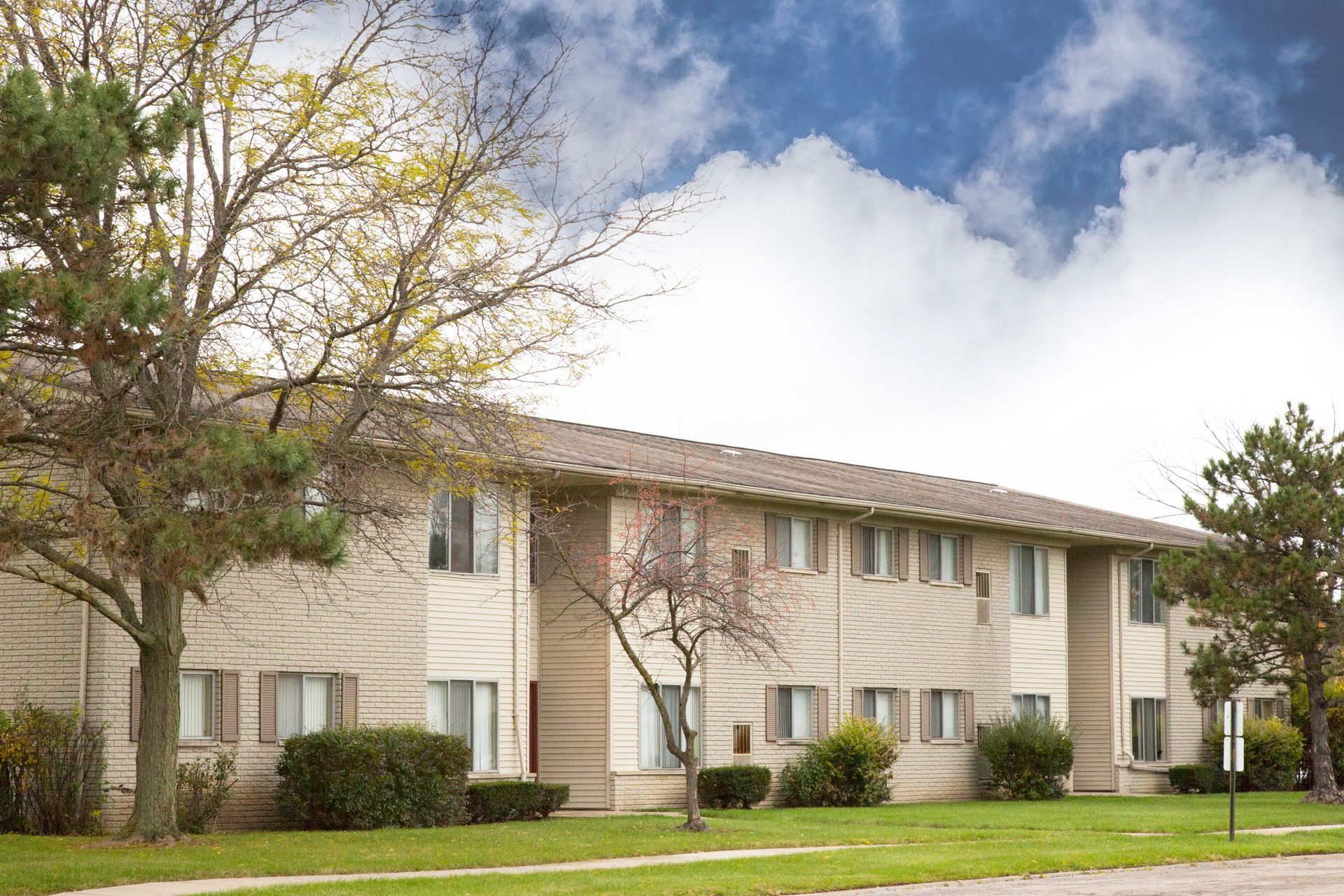 A large apartment building with a lot of windows and trees in front of it.