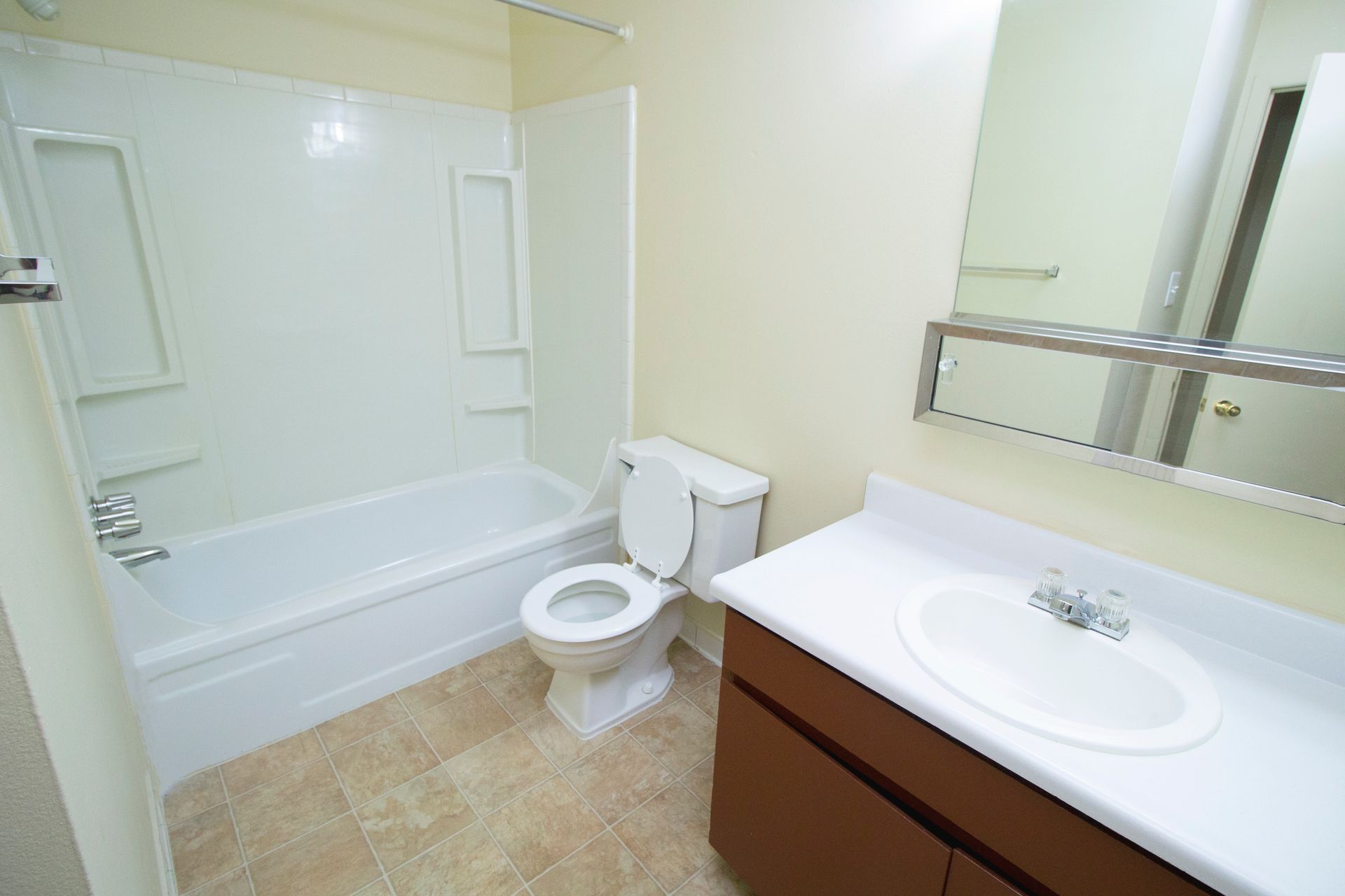 A bathroom with a toilet , sink , bathtub and mirror.