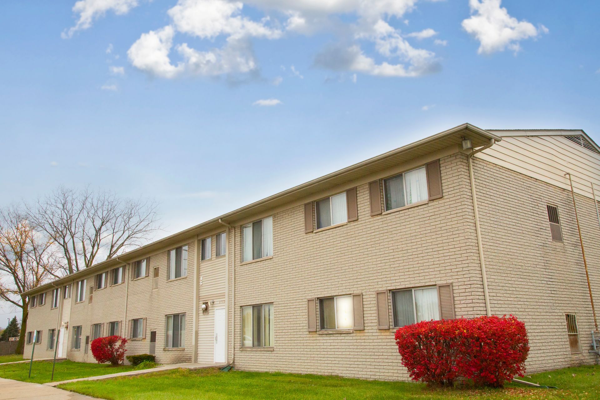 A large apartment building with a lot of windows and a bush in front of it.