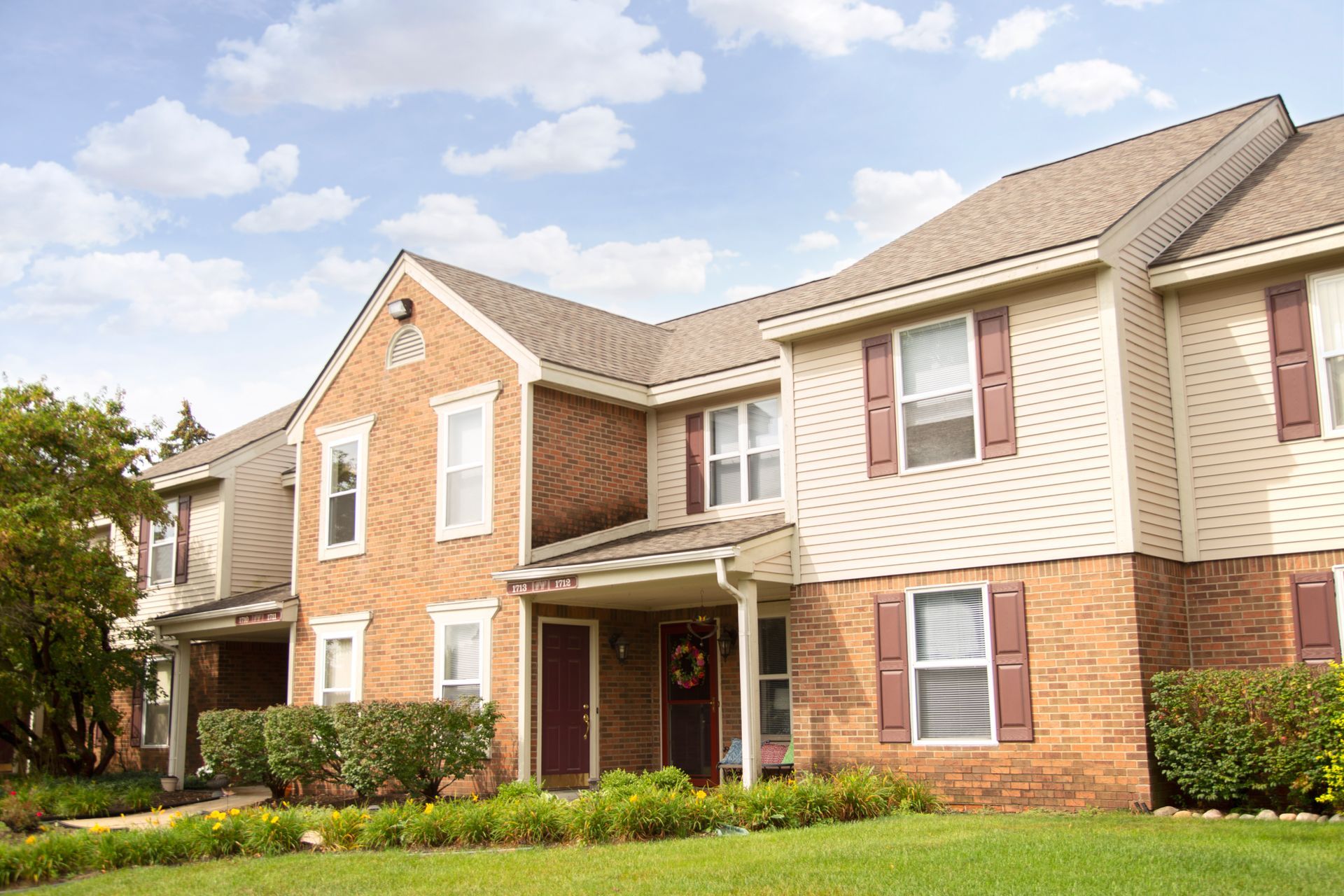 A large brick apartment building with a lush green lawn in front of it.