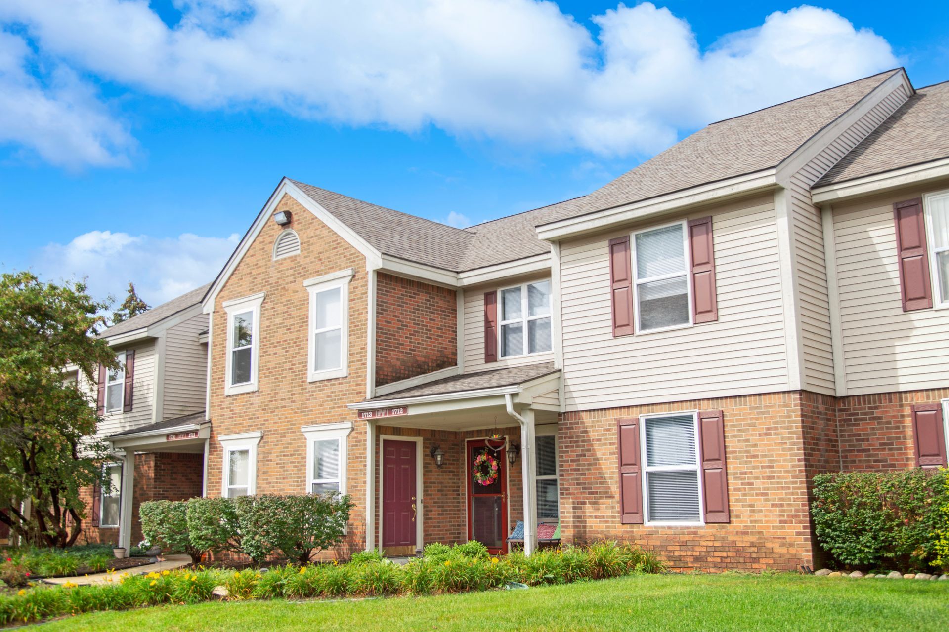 A large brick apartment building with a lush green lawn in front of it.