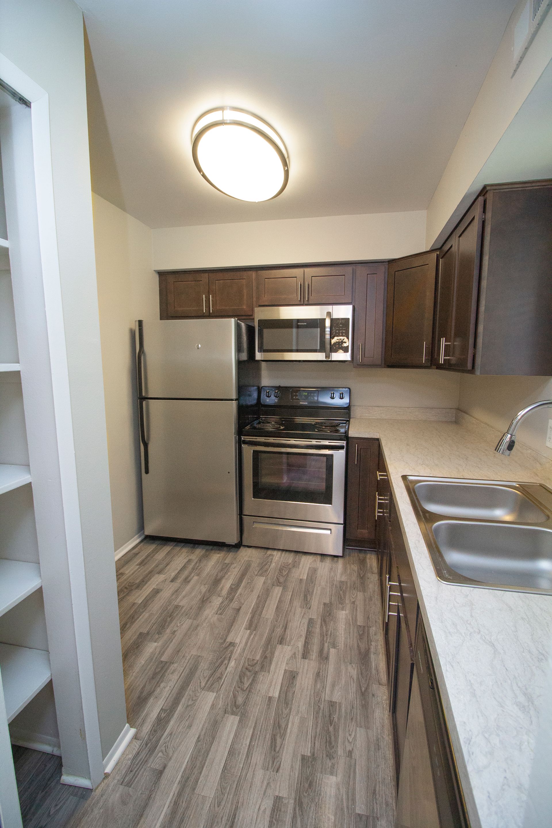 A kitchen with a refrigerator , stove , microwave and sink.