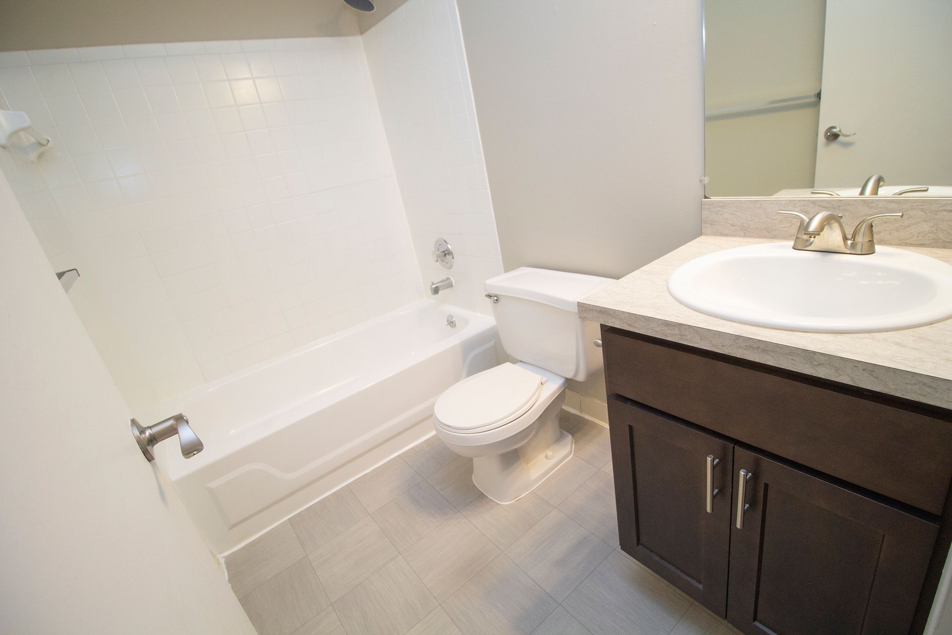 A bathroom with a toilet , sink , bathtub and mirror.