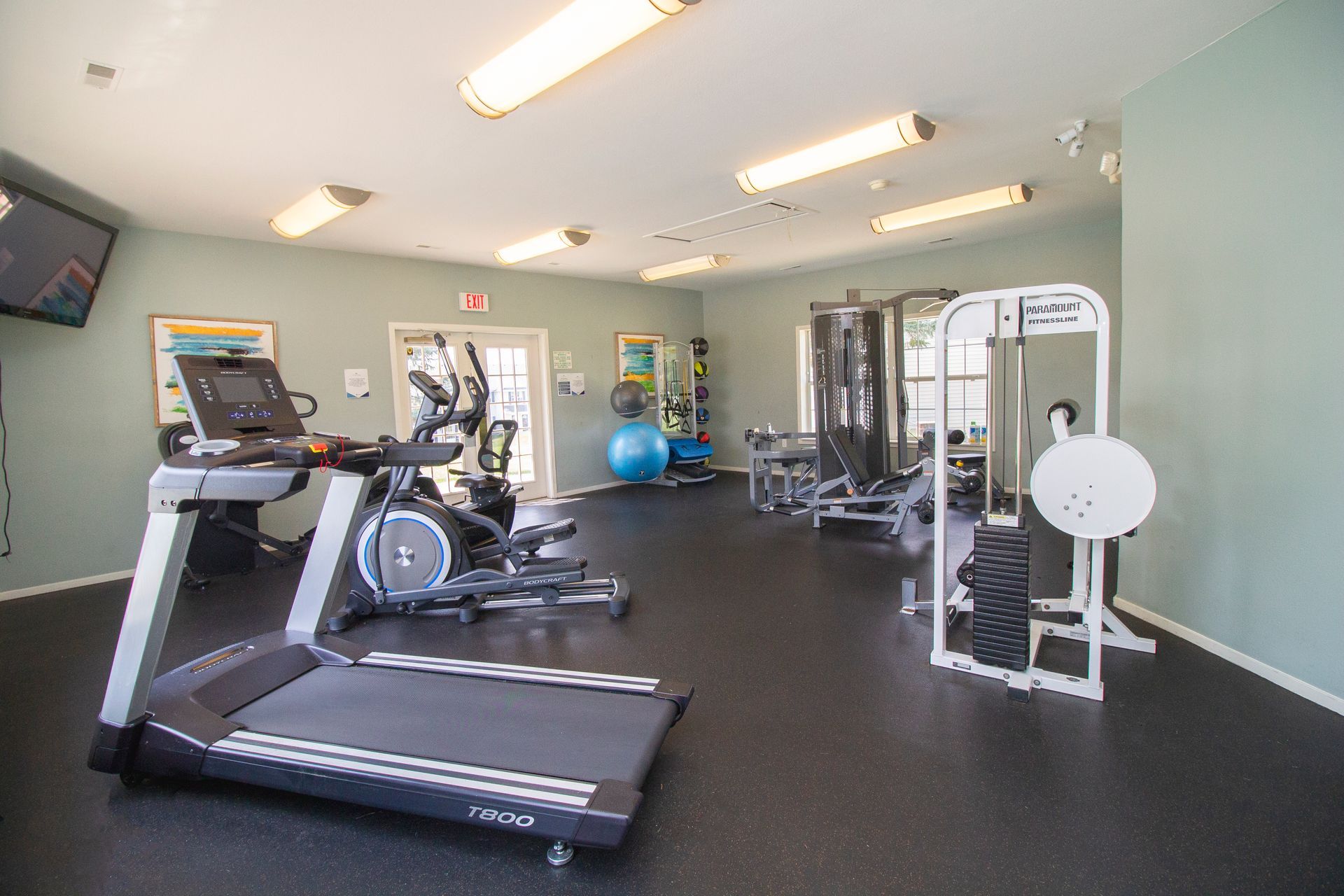 A gym with a treadmill , elliptical , and other exercise equipment.