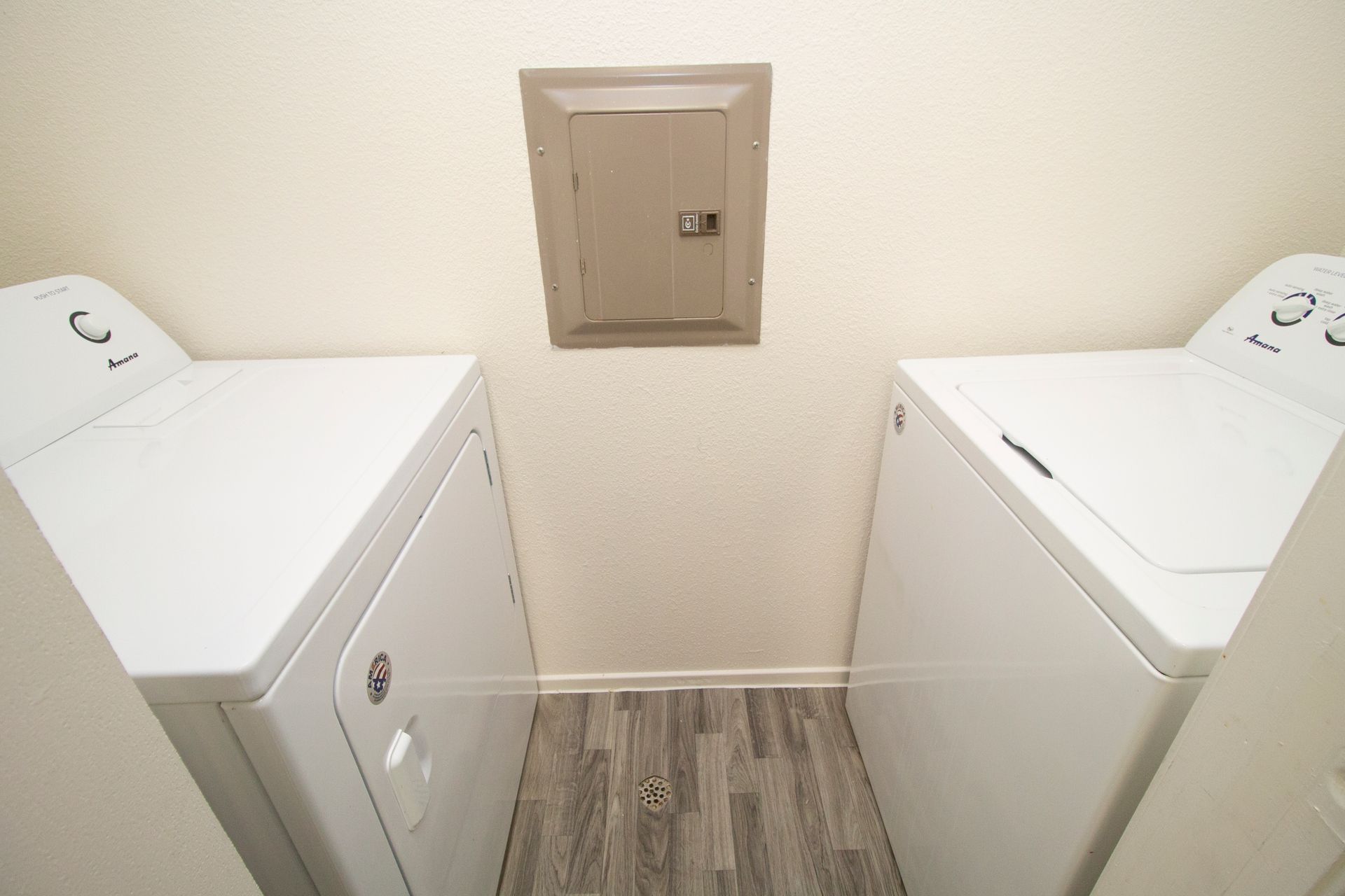A laundry room with two white washers and dryers