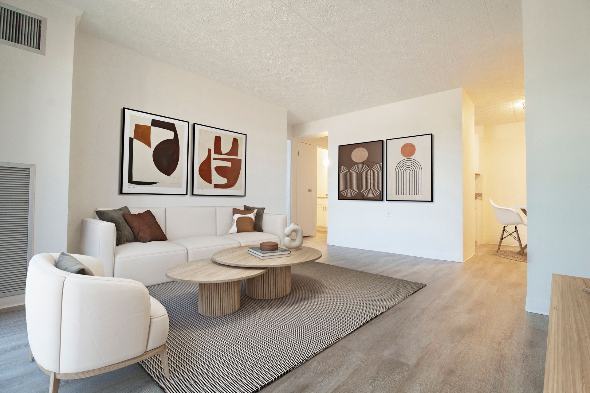 A living room with a couch , chairs , coffee tables and paintings on the wall.