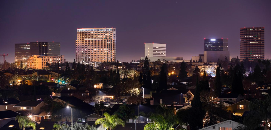A city skyline at night with a lot of buildings lit up Private Investigator Costa Mesa