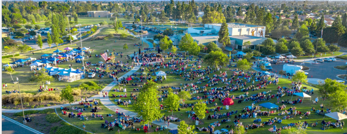 An aerial view of a large crowd of people sitting in a park.