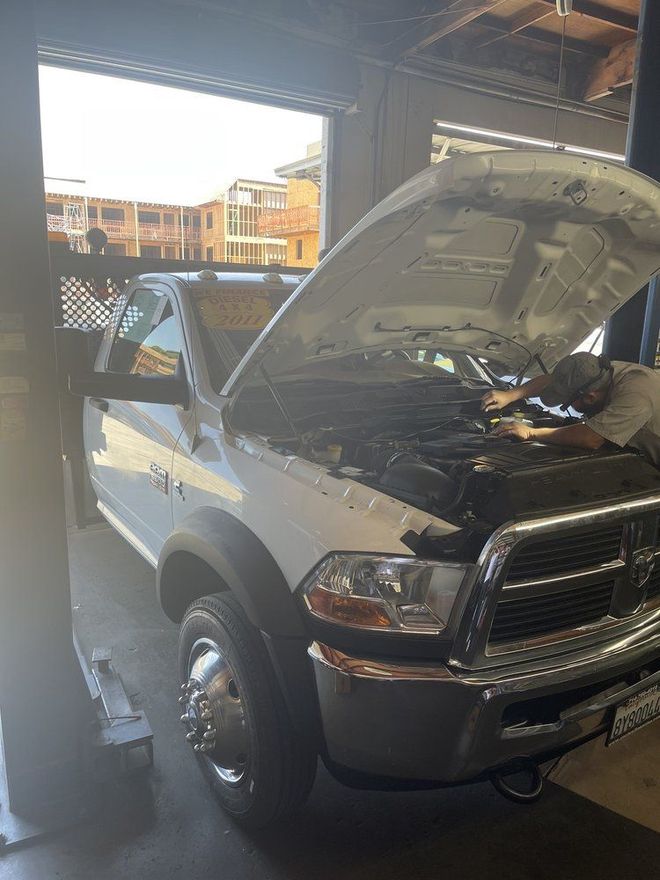 A man is working on a truck with the hood open in a garage.