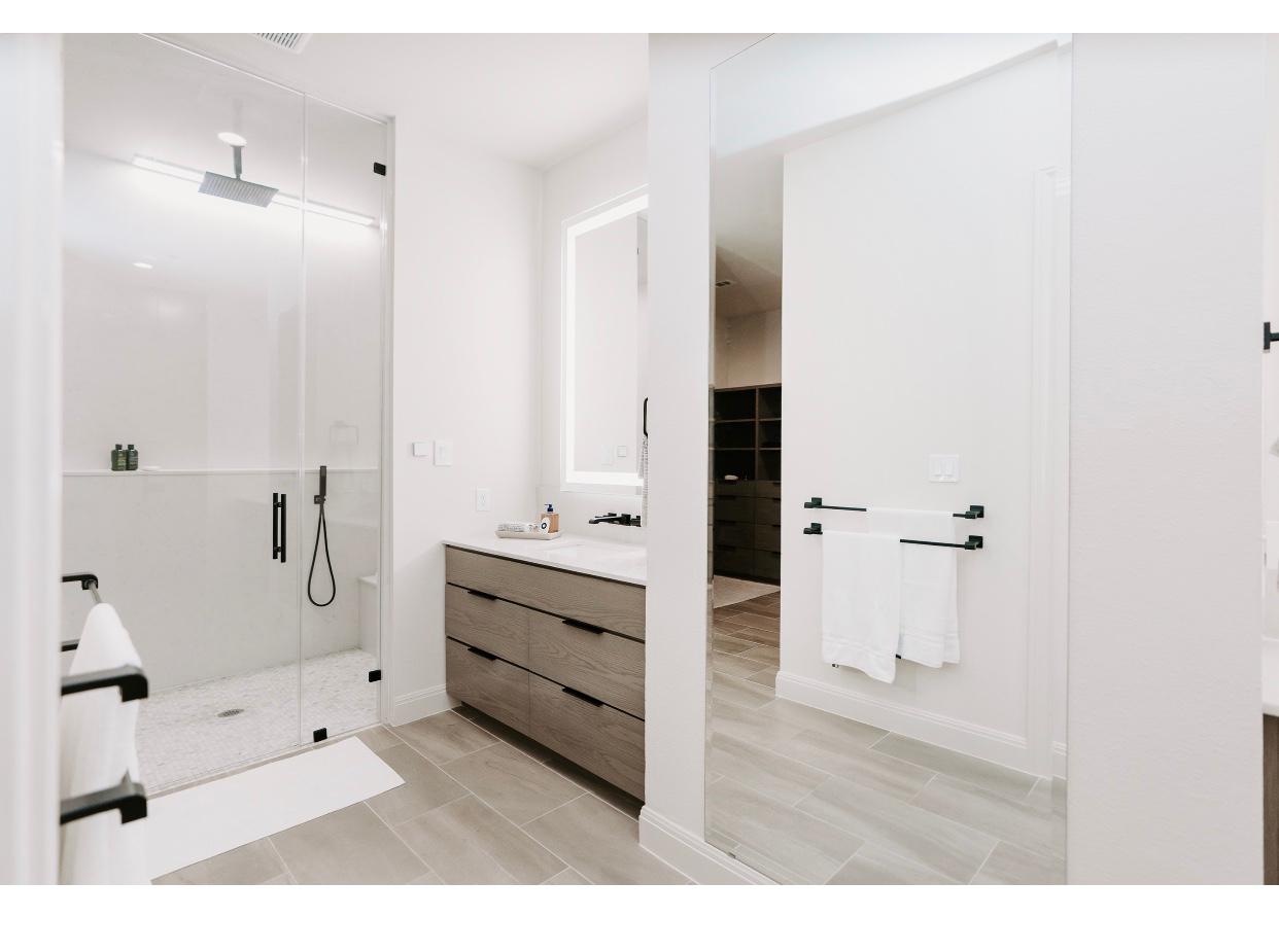 A bathroom with a walk in shower , sink and mirror.