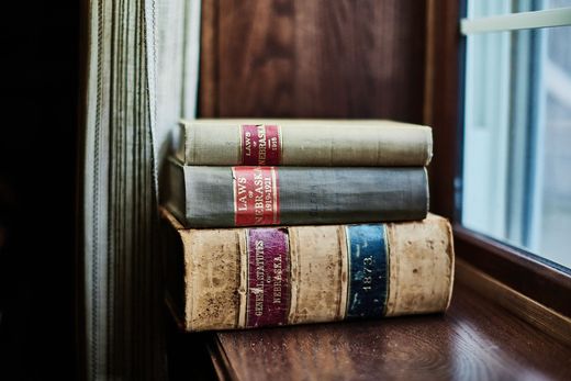 Three books are stacked on top of each other on a window sill.