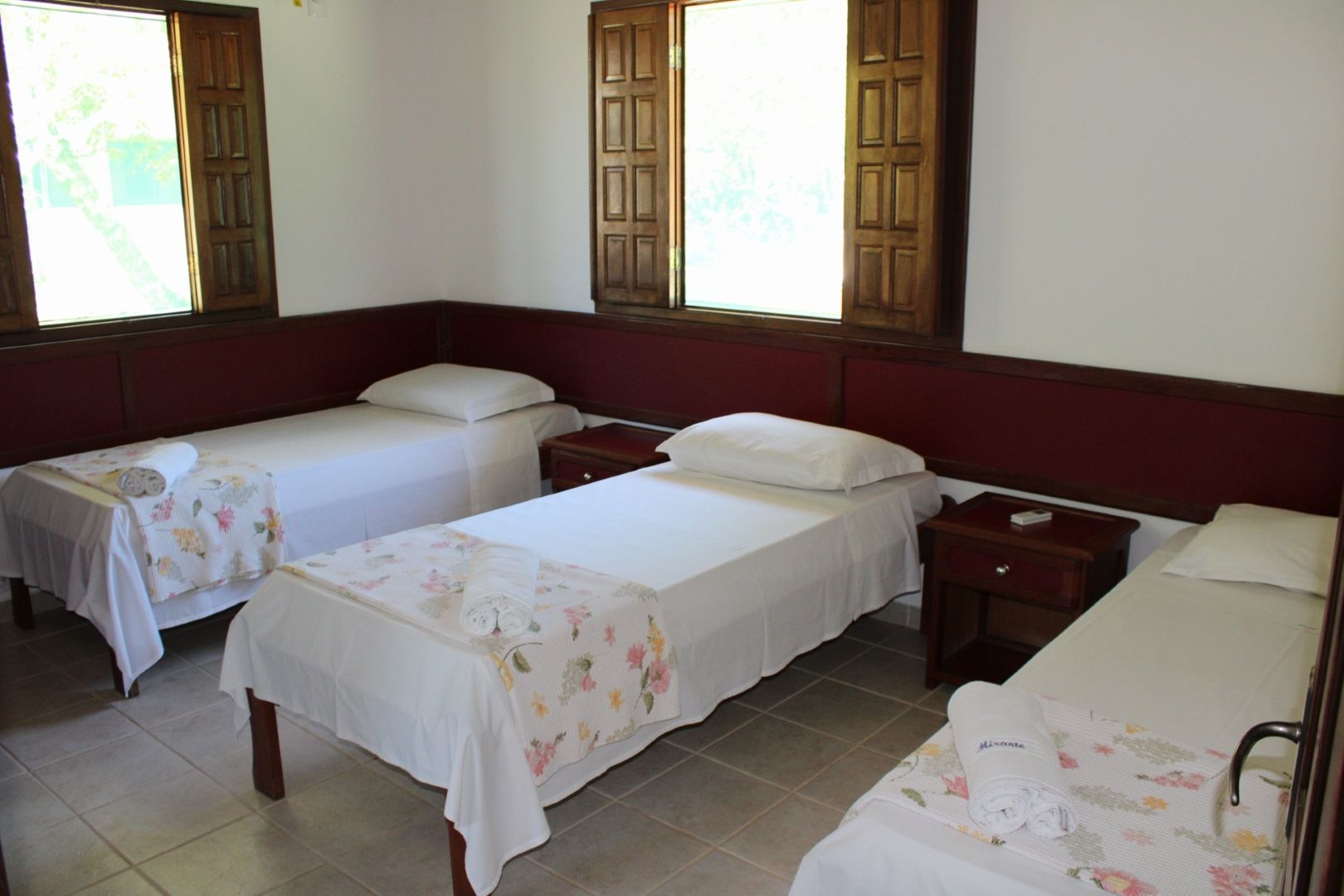 Um quarto com três camas e duas janelas