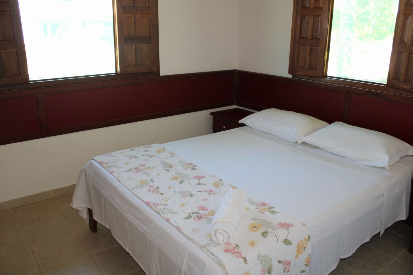 Um quarto com uma cama e duas janelas com venezianas