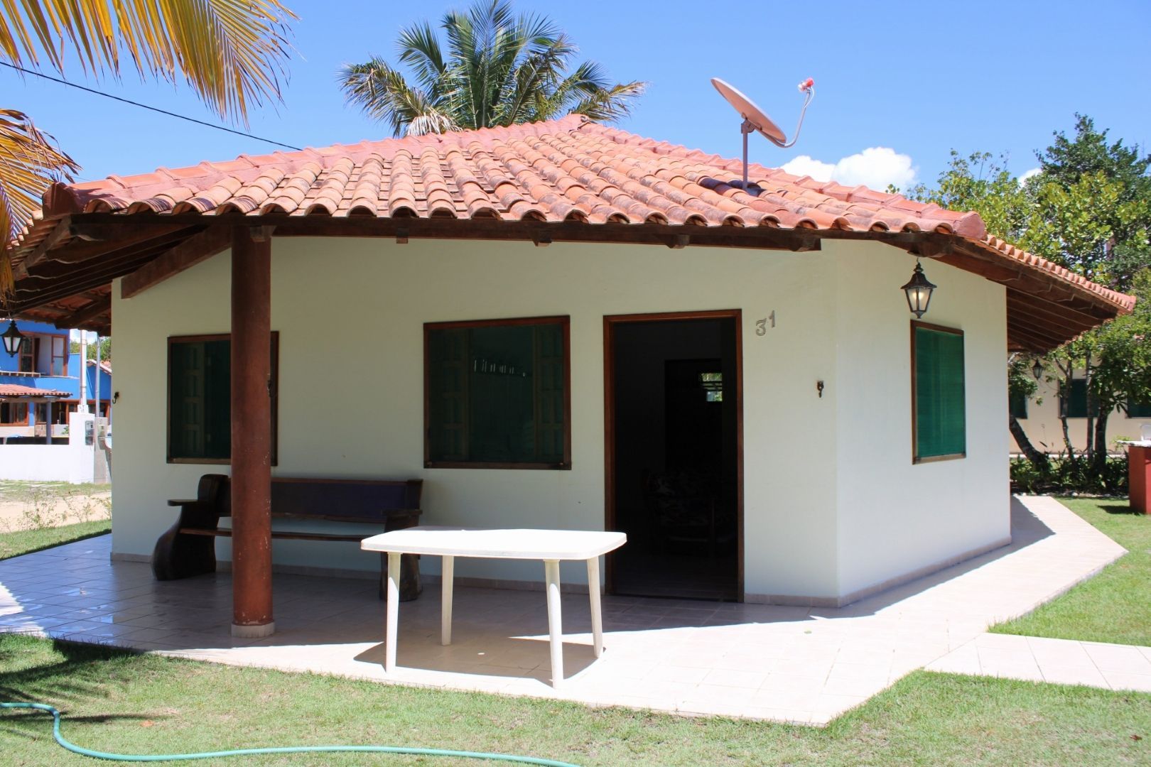 Uma pequena casa branca com telhado de telha vermelha