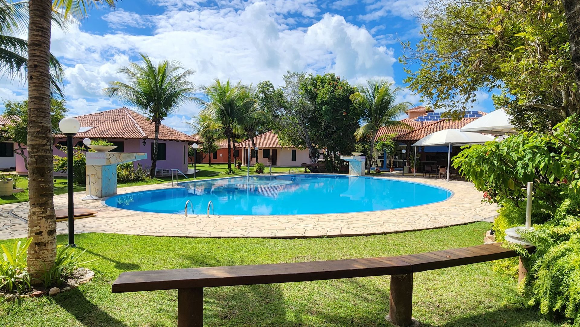 Há uma grande piscina no meio de um jardim verdejante.