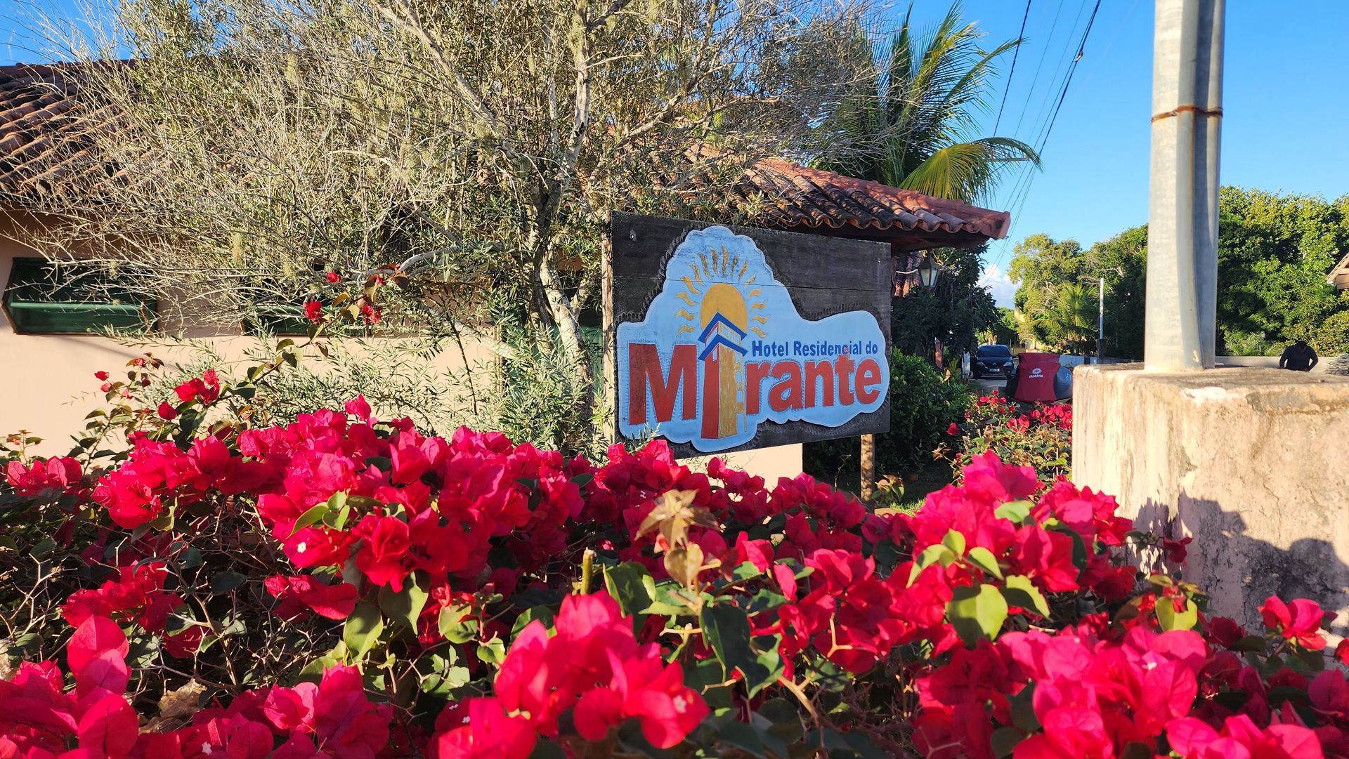 Uma placa para mirame é cercada por flores rosas.