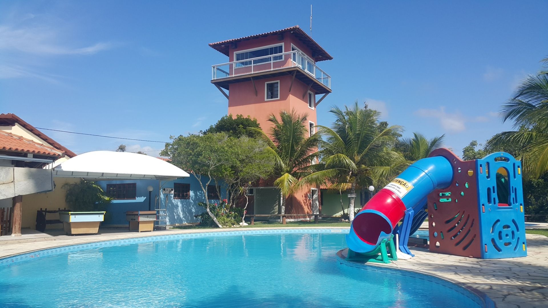 Uma piscina com um escorregador e uma torre ao fundo