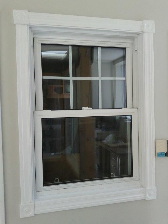 Une fenêtre blanche avec une bordure blanche est accrochée à un mur