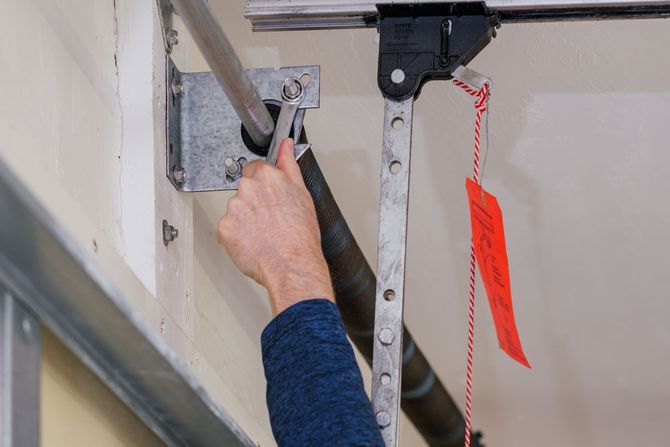 Une personne répare une porte de garage avec une clé.