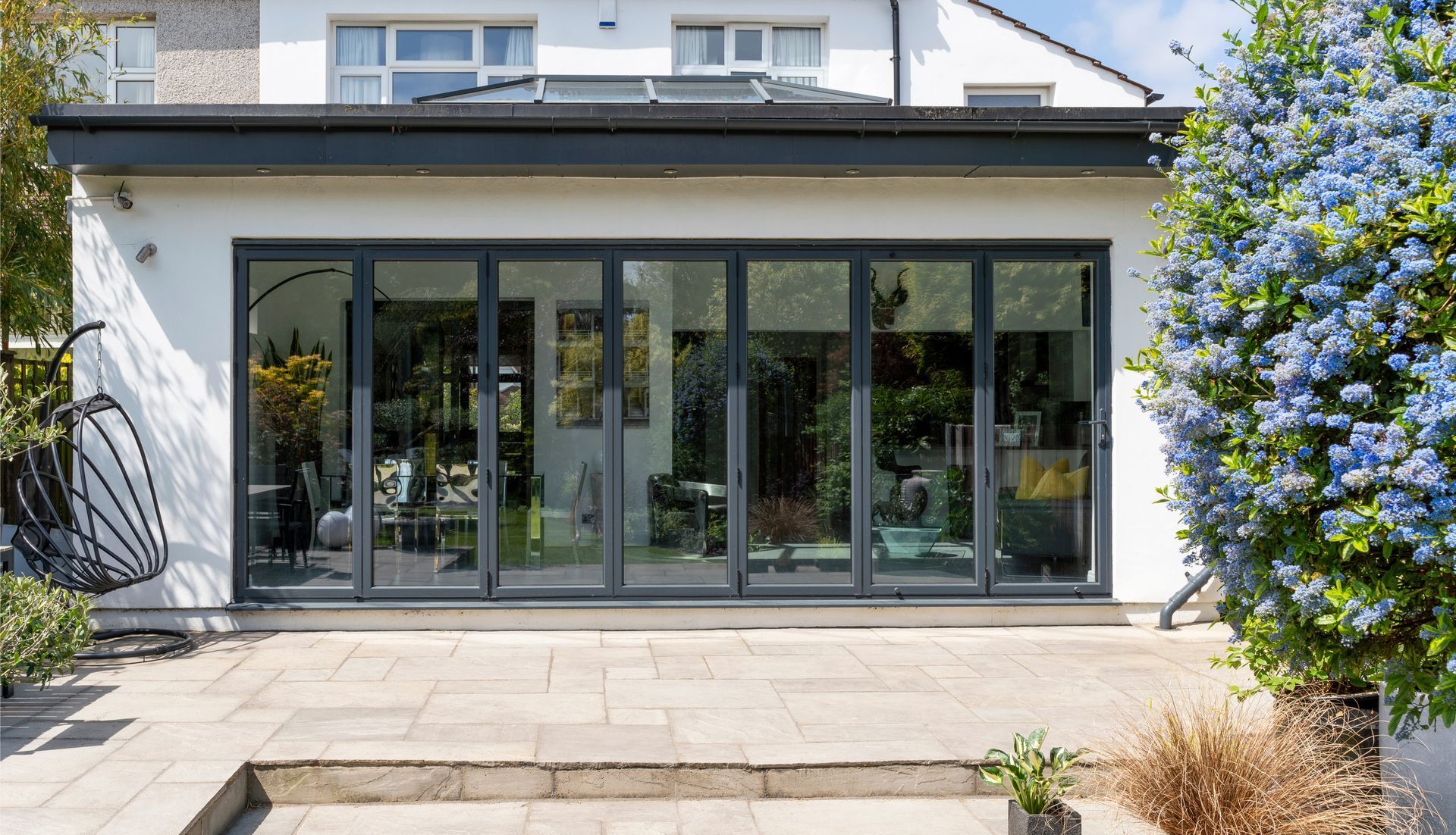 L'arrière d'une maison avec beaucoup de fenêtres et un patio.