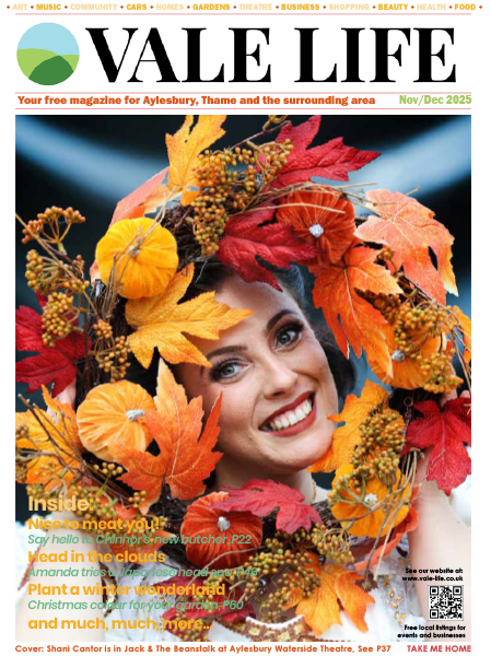 Cover of Vale Life magazine featuring the face of actress Shani Cantor, who plays The Spirit of the Beans in the Jack & The Beanstalk pantomime at Aylesbury Waterside theatre for 2025 looking through the centre of an autumn wreath in gorgeous red, yellow and orange colours.