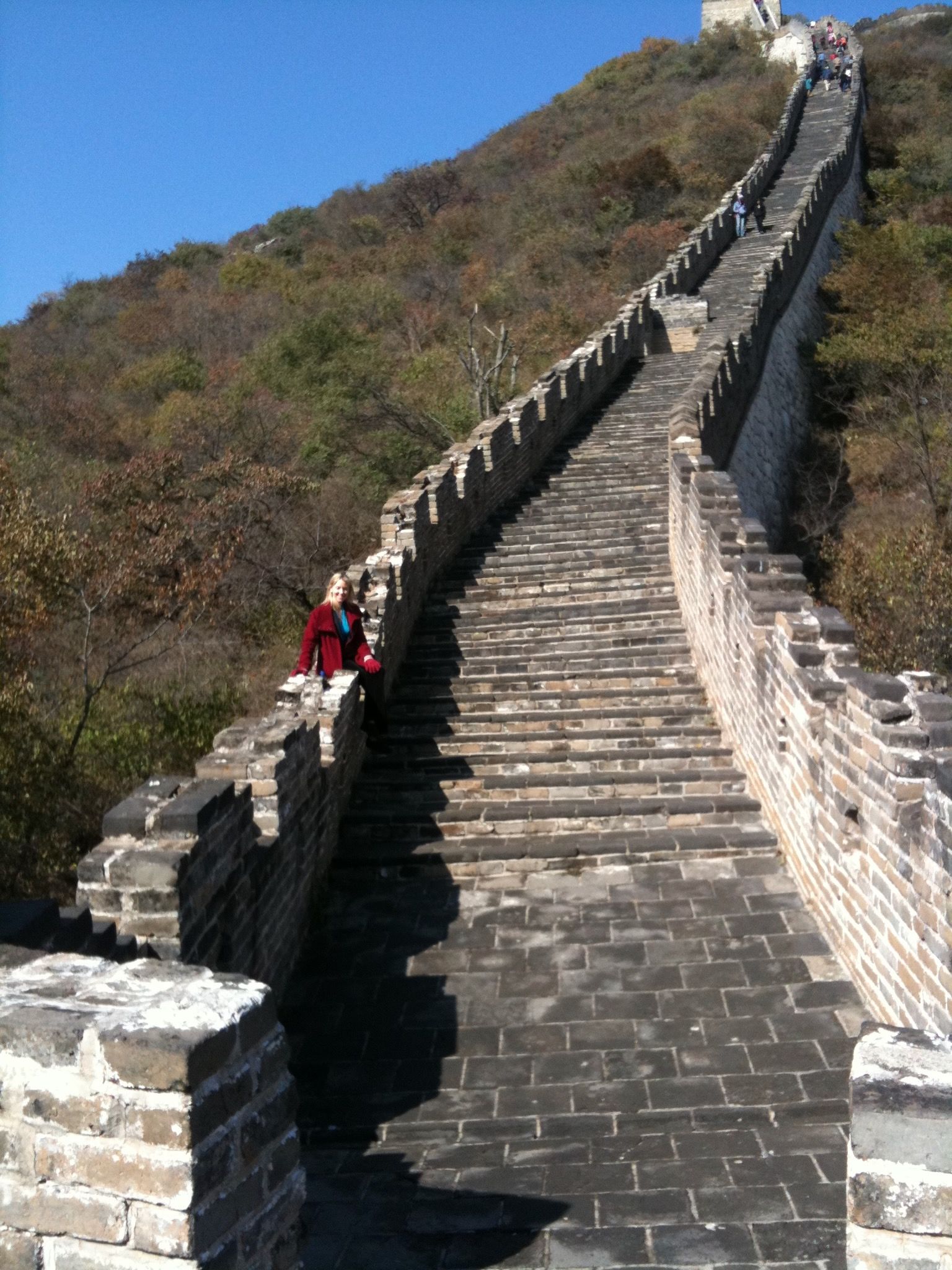 A woman in a red jacket stands on the side of the great wall of china
