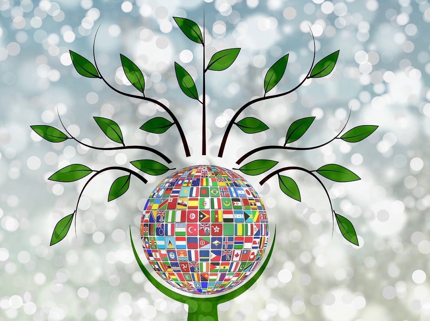 A globe with flags on it is surrounded by branches and leaves.