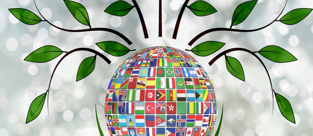 A globe with flags on it is surrounded by branches and leaves.