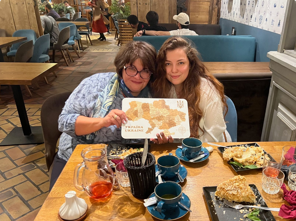 Two women are sitting at a table in a restaurant holding a plate of food.