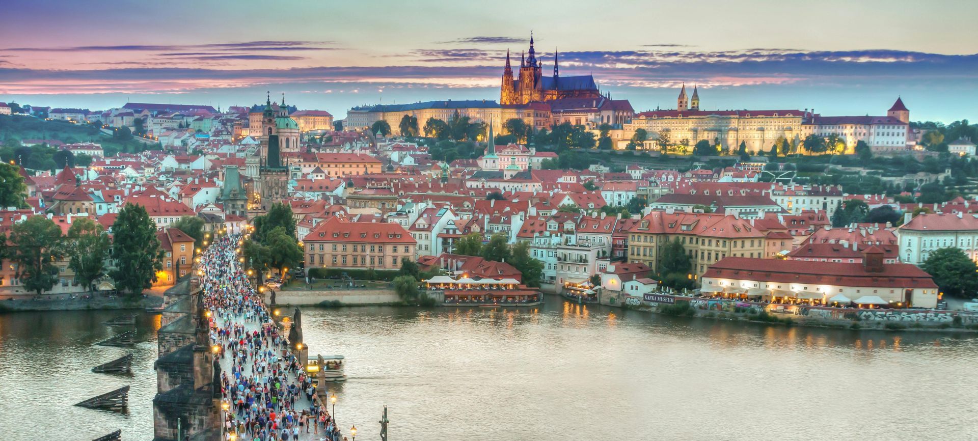 An aerial view of a city with a bridge over a river and a castle in the background.