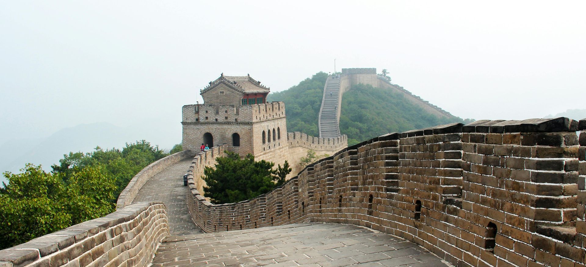 A view of the great wall of china from the top of a hill.