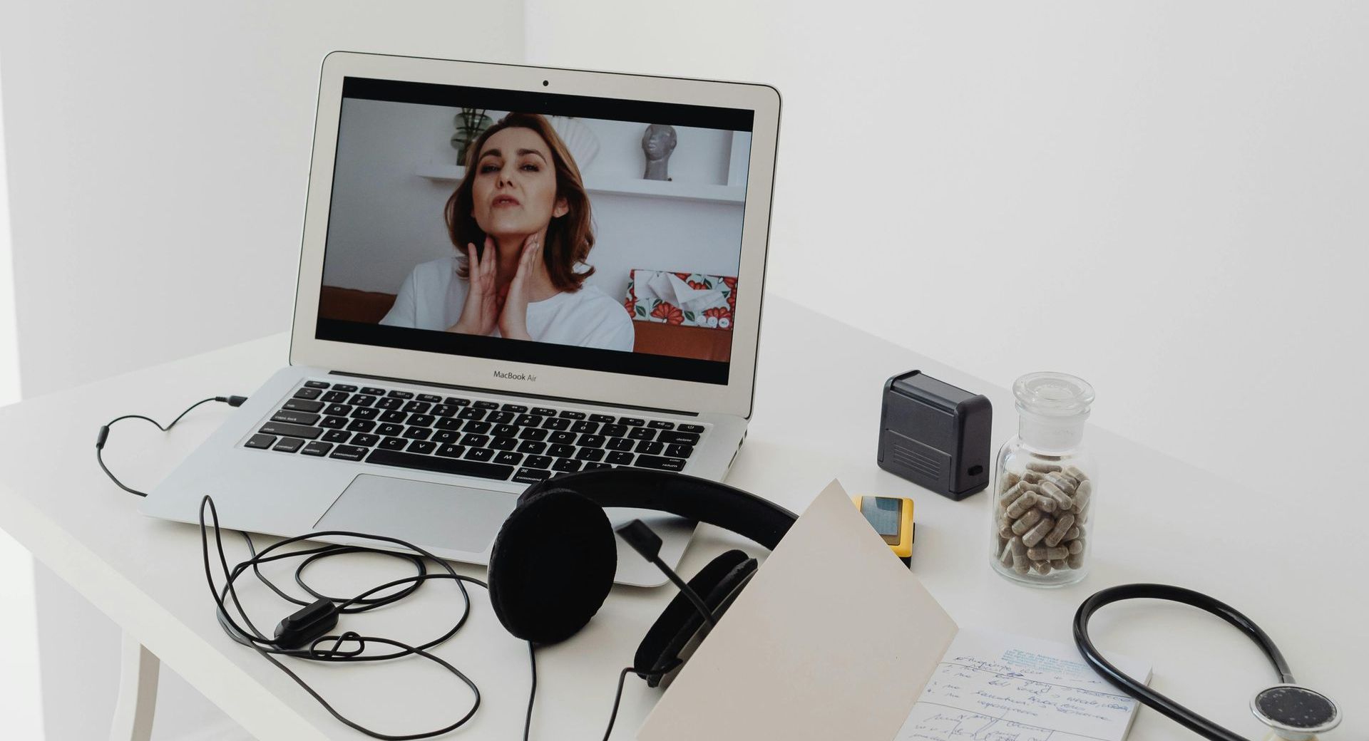 A laptop computer with headphones and a stethoscope on a table.
