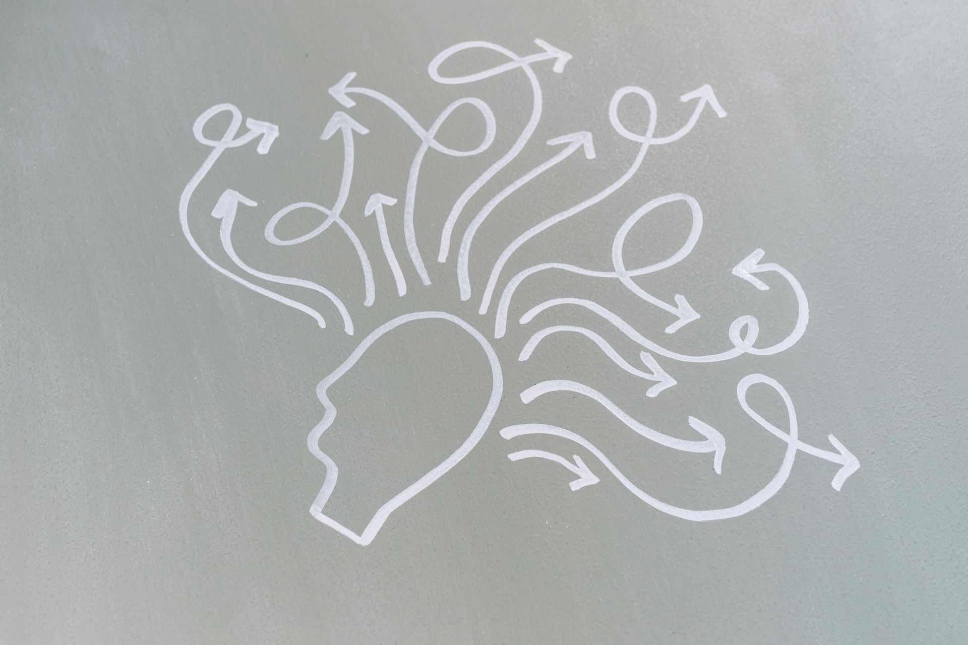 White outline of a head with arrows spiraling outwards, suggesting many thoughts or ideas.