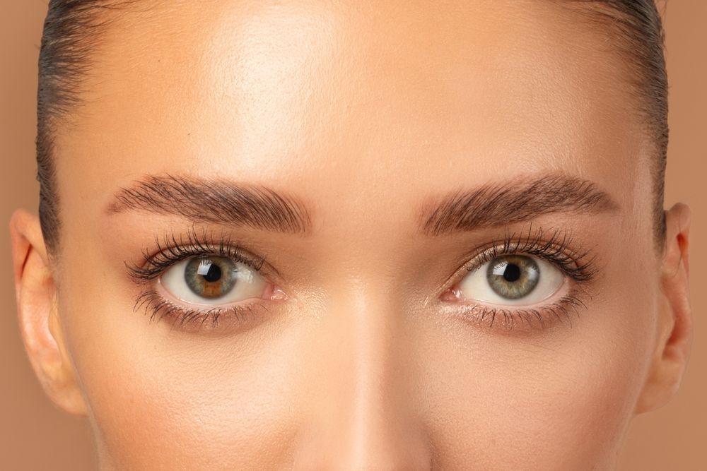 Close-up of a person's face. Light skin, green eyes, full eyebrows, and a neutral expression.