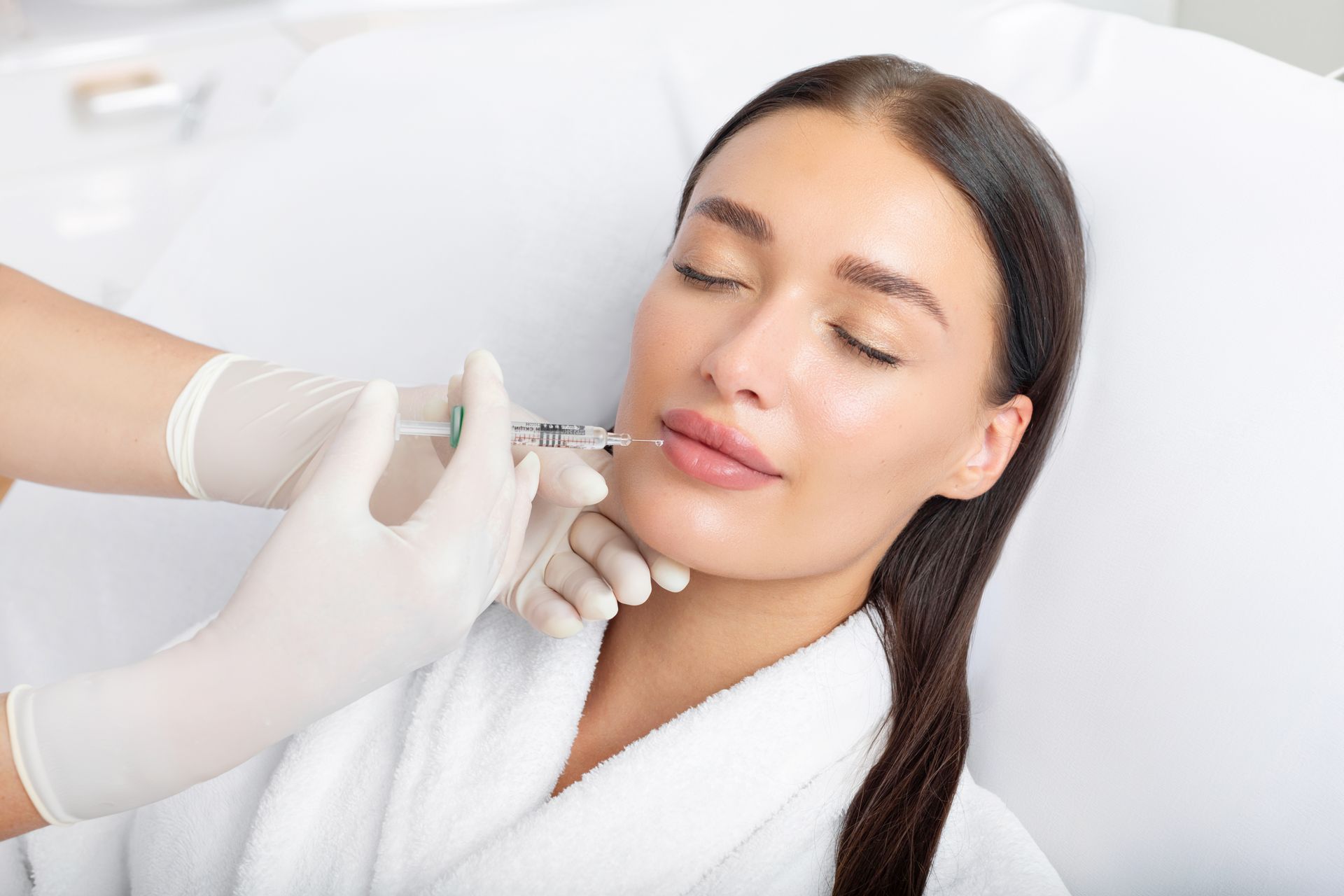 A woman is getting a botox injection in her lips.