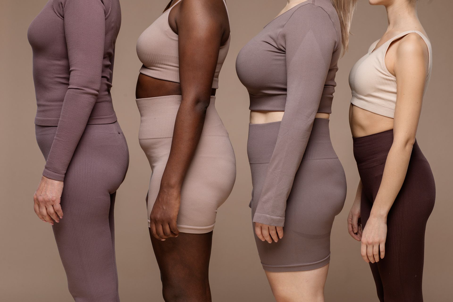 Four women of different sizes and races are standing next to each other.