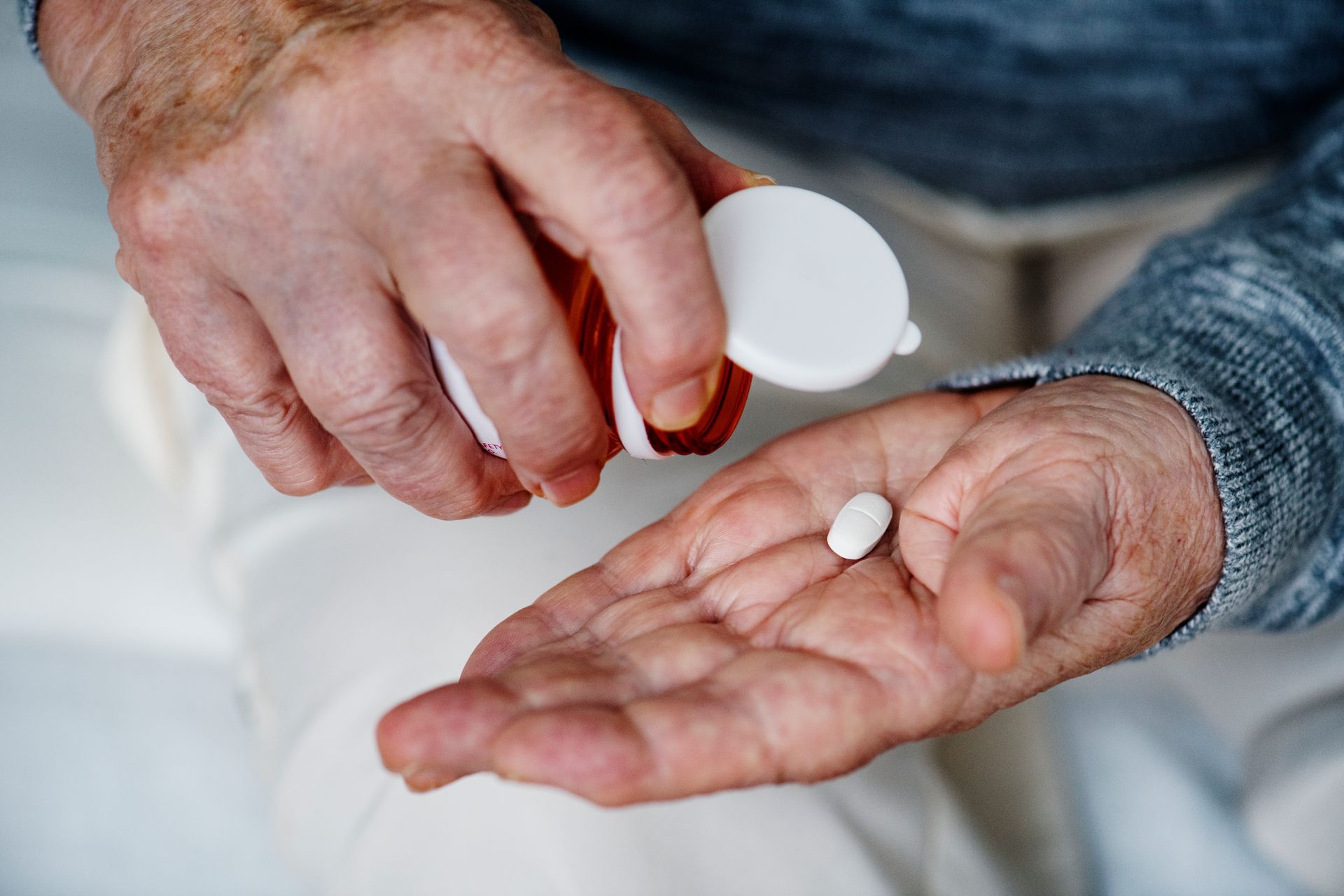 A man is pouring a pill from a bottle into his hand.
