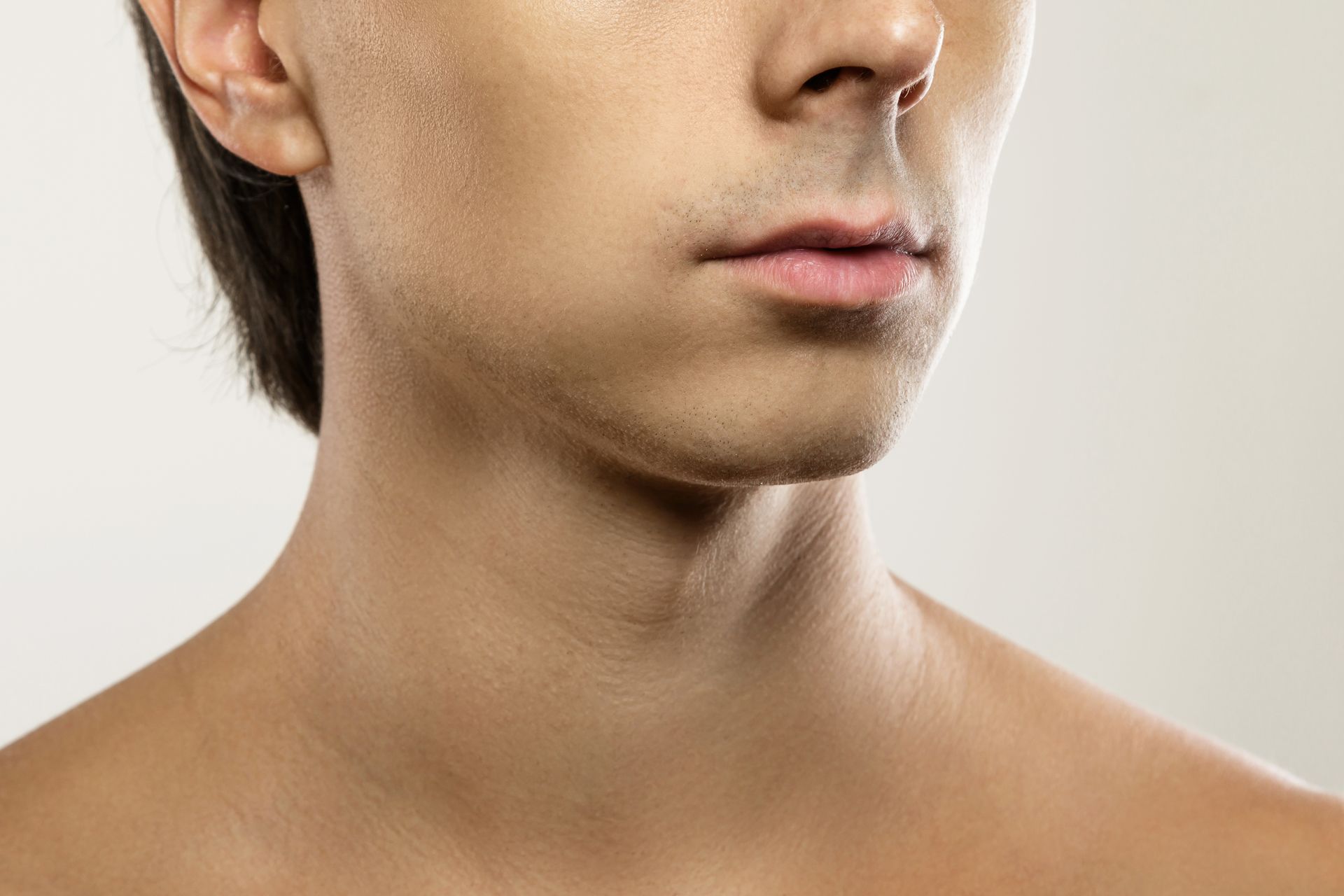 A close up of a man 's jawline and neck without a shirt.