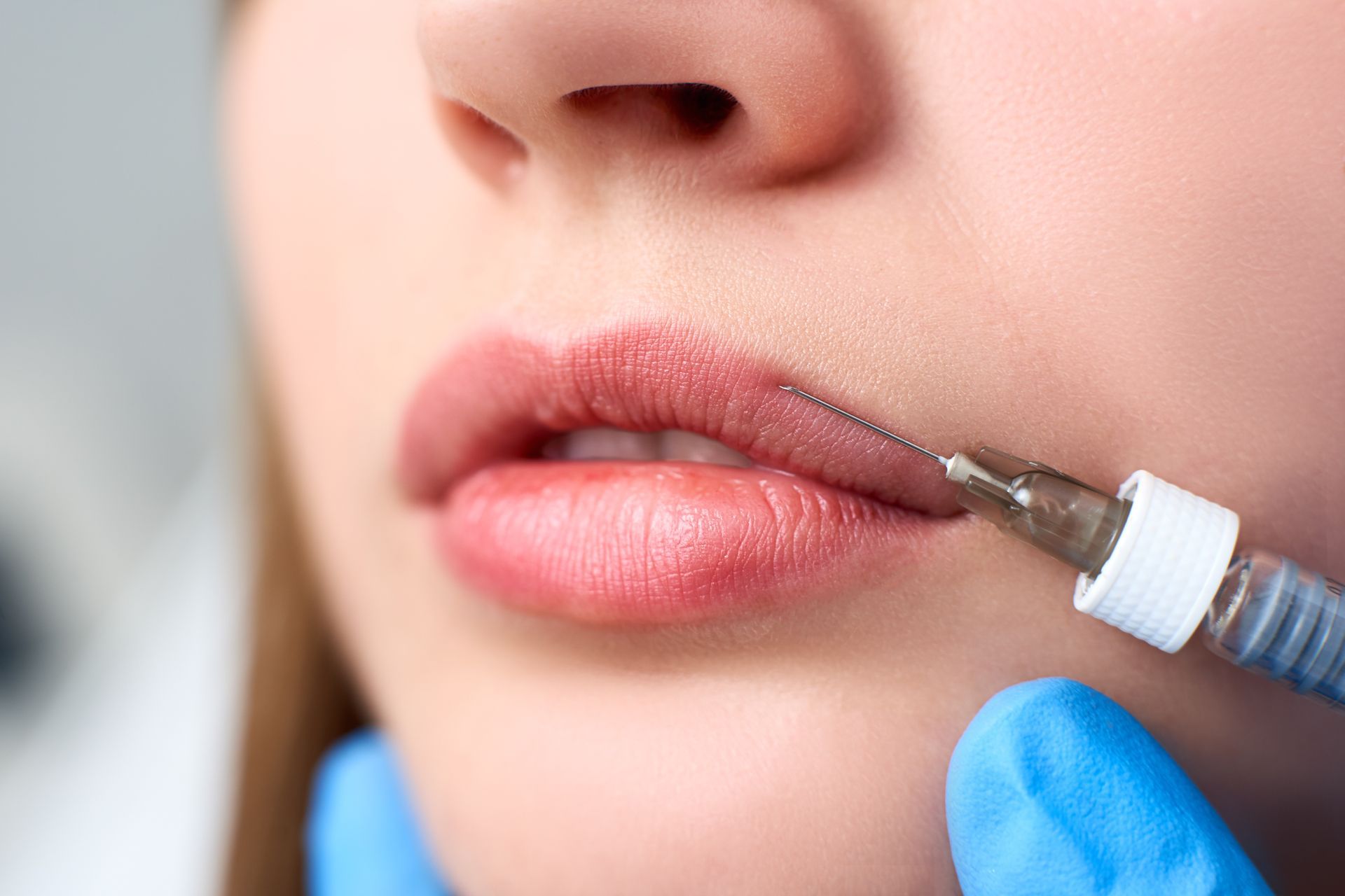 a woman is getting a lip filler with a syringe .